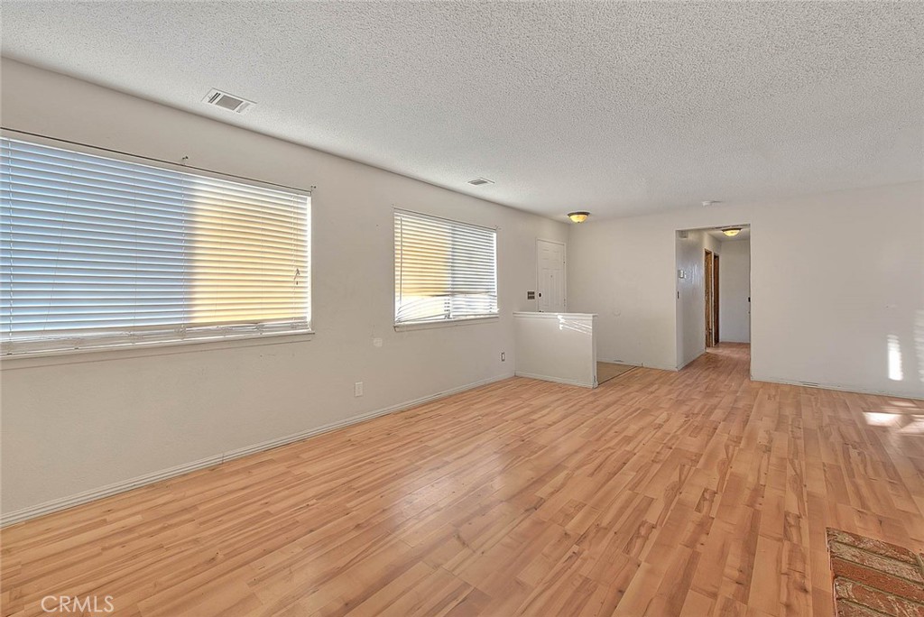 14811 Kingsdale Road Apple Valley, CA 92307 - Photo 9 of 57 a view of an empty room with wooden floor and a window