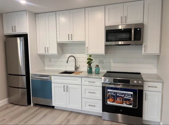 a kitchen with appliances a sink and cabinets
