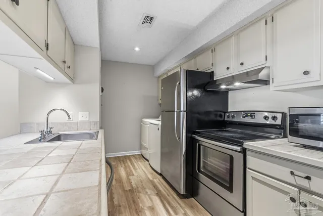 a kitchen with granite countertop a sink stainless steel appliances and cabinets