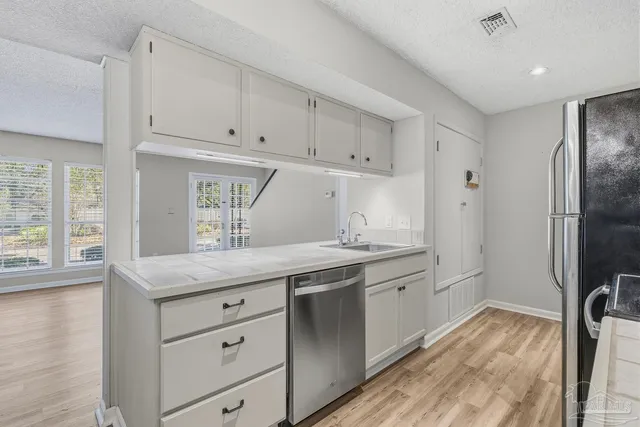 a kitchen with granite countertop a sink a counter space appliances and cabinets
