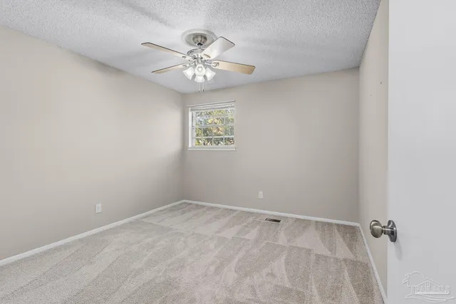 an empty room with a chandelier fan and windows