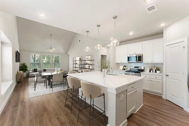 a large white kitchen with lots of counter space and stainless steel appliances