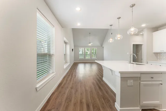 a view of a kitchen with kitchen island a sink wooden floor and a large window