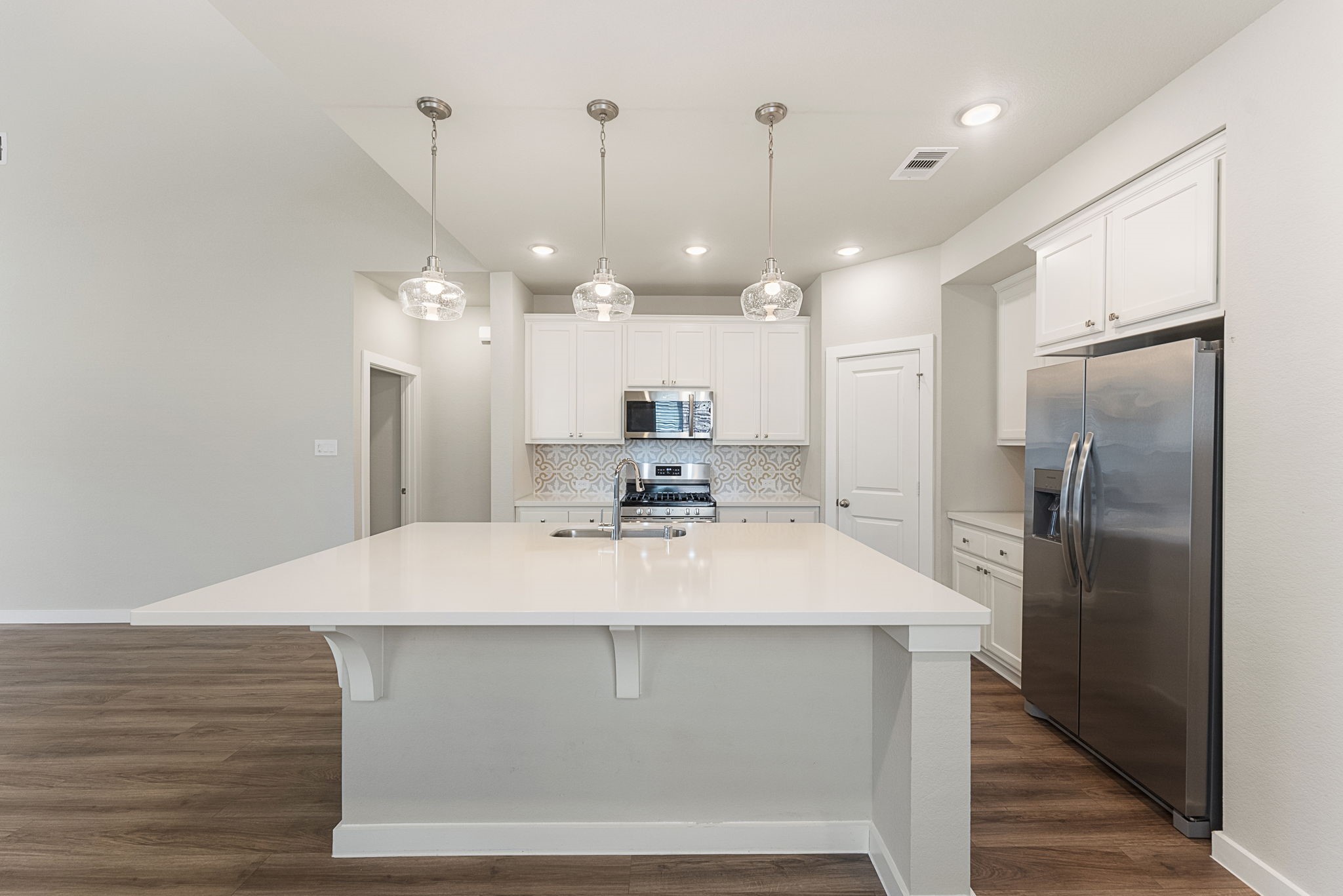 421 Soapberry Tree Court Conroe, TX 77318 - Photo 8 of 50 a large kitchen with a refrigerator a sink and a wooden floor