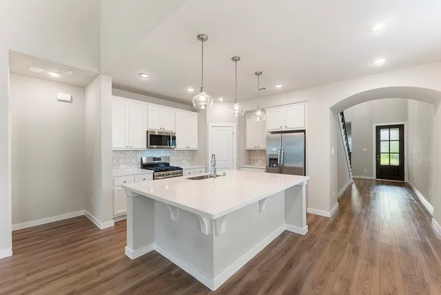 a large white kitchen with wooden floor and a refrigerator