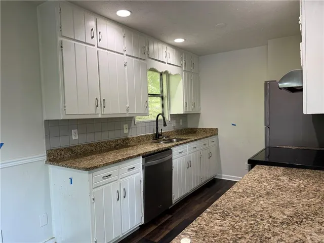 a kitchen with granite countertop white cabinets white appliances a sink and a stove