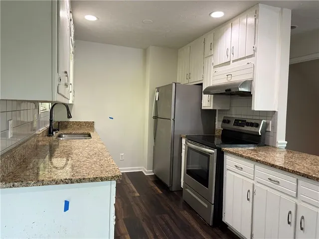 a kitchen with granite countertop a refrigerator stove and sink
