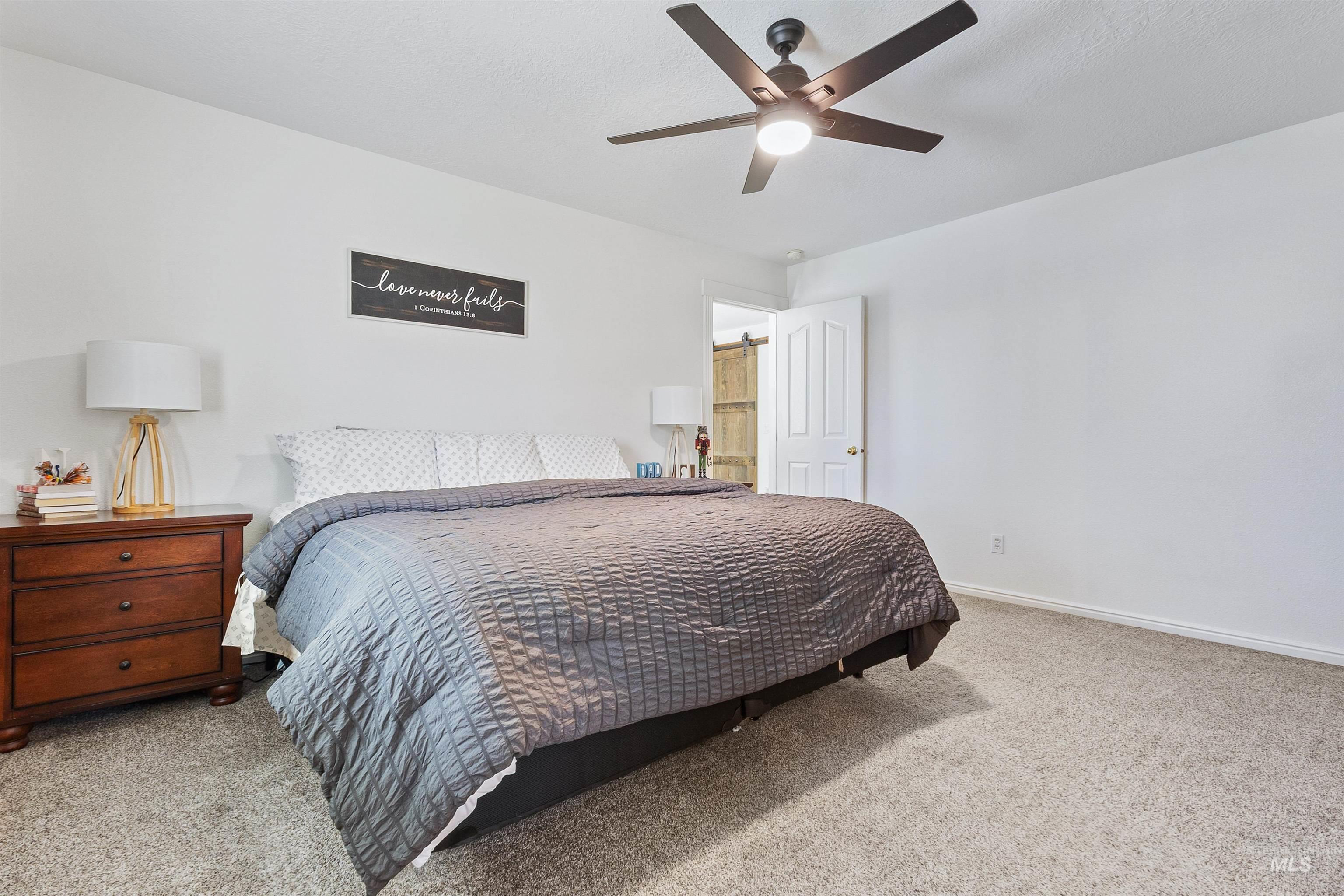19876 Scotts Lane Caldwell, ID 83607 - Photo 35 of 44 Bedroom featuring light-colored carpet, a ceiling fan with integrated lighting, and a paneled door