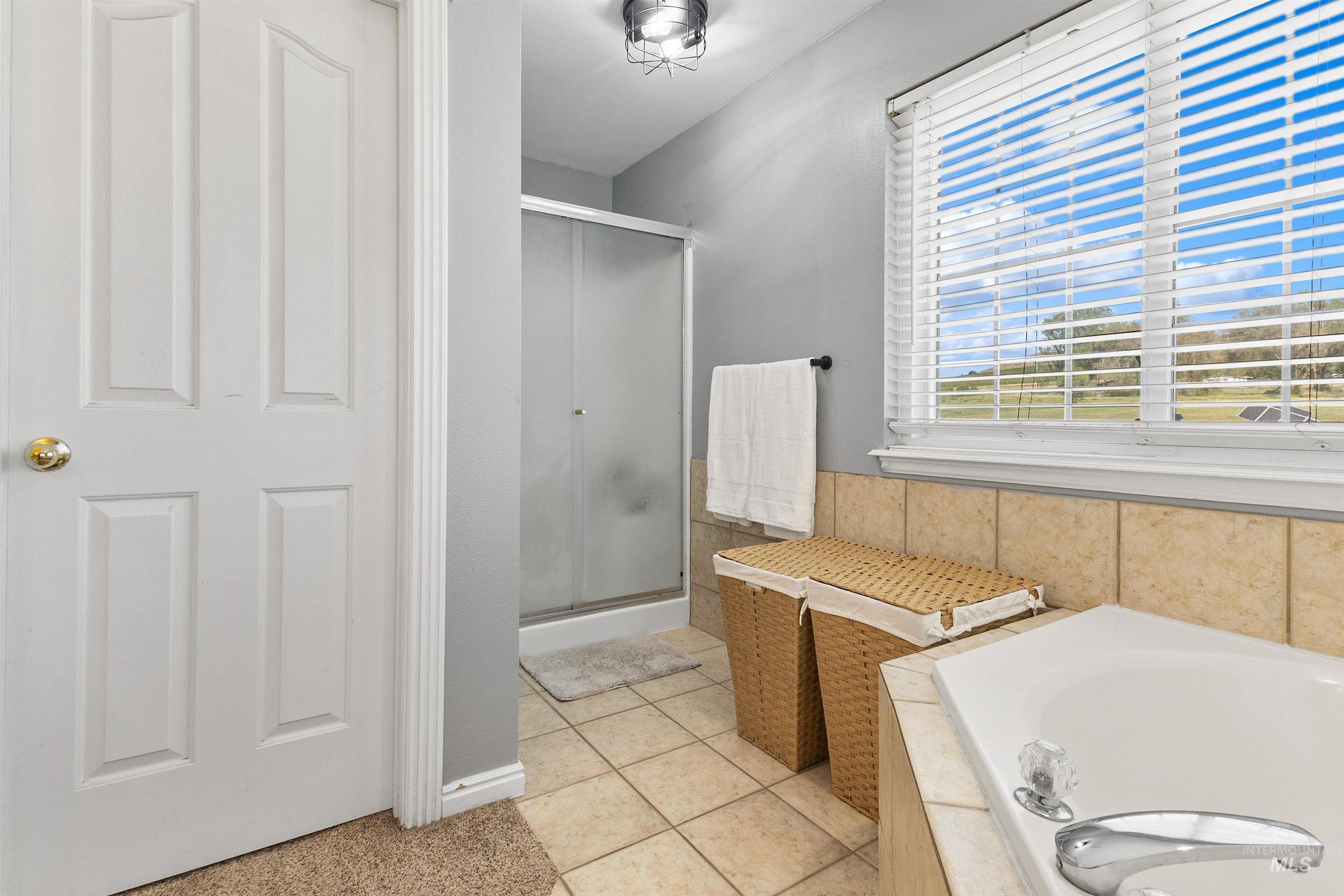 19876 Scotts Lane Caldwell, ID 83607 - Photo 36 of 44 Bathroom featuring a built-in bathtub, a walk-in shower with a glass enclosure, and a window with horizontal blinds