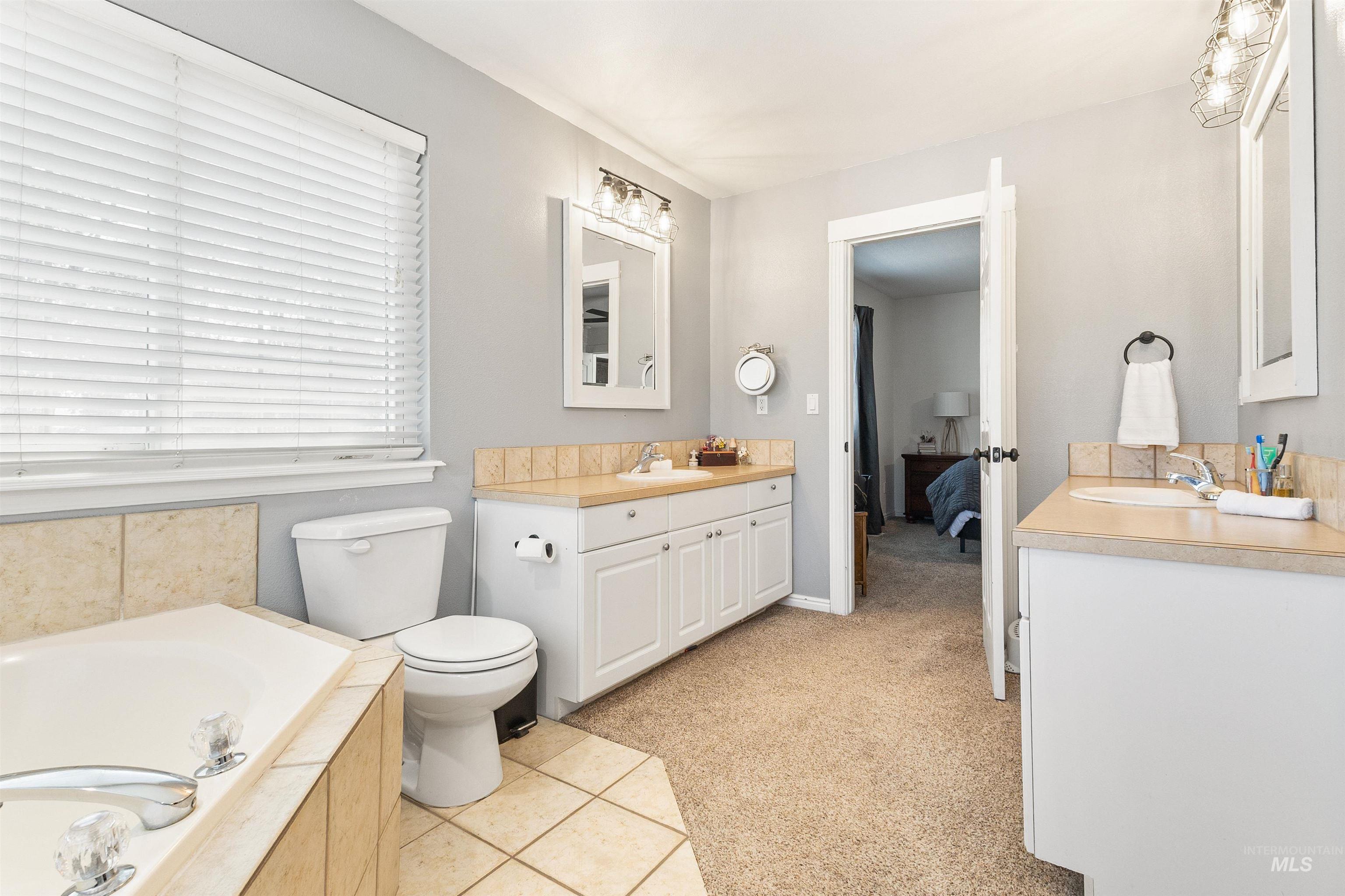 19876 Scotts Lane Caldwell, ID 83607 - Photo 38 of 44 Spacious bathroom with a large corner soaking tub, dual vanity areas featuring wood-finish countertops, and a separate commode