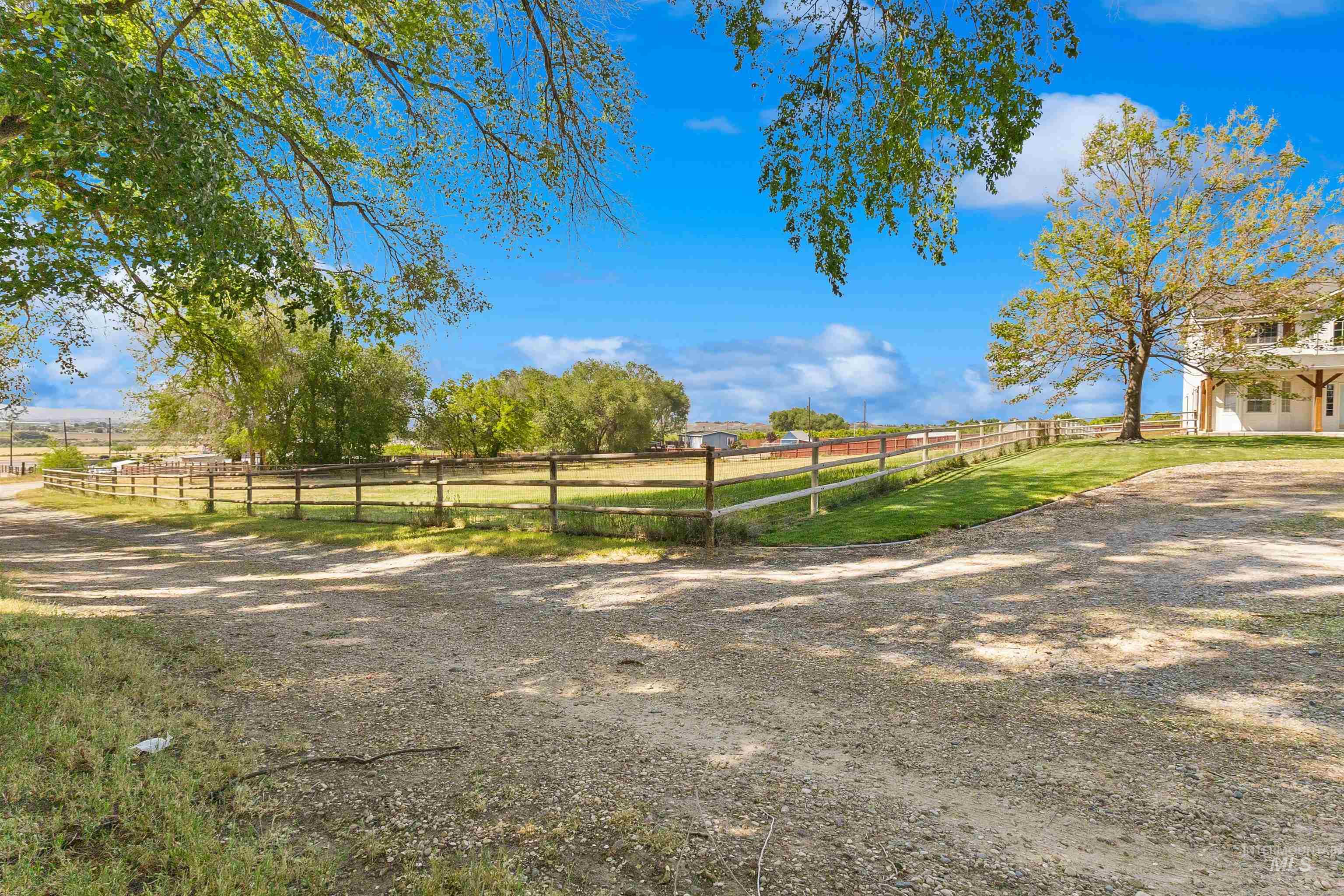 19876 Scotts Lane Caldwell, ID 83607 - Photo 4 of 44 Expansive gravel driveway bordered by a wooden fence and grassy fenced pasture.