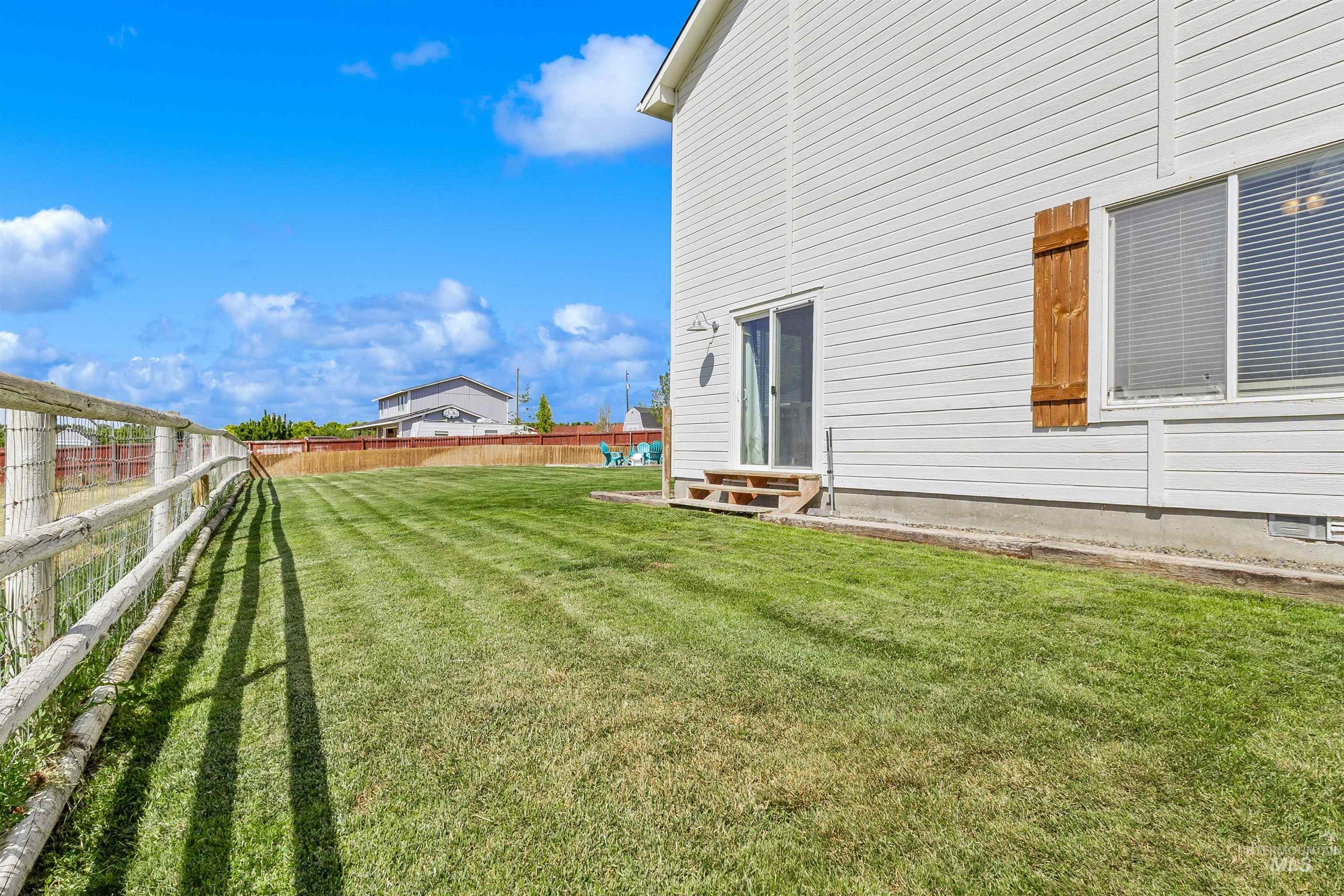 19876 Scotts Lane Caldwell, ID 83607 - Photo 7 of 44 Expansive green lawn with a white split-rail fence, pasture, and patio door into the formal dining area.