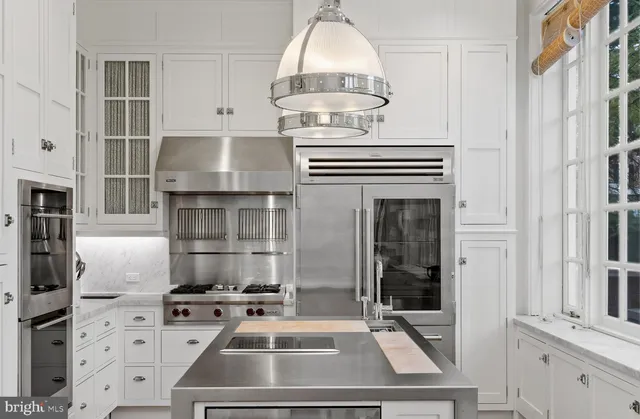 a large white dining hall with stainless steel appliances granite countertop a stove and a large window