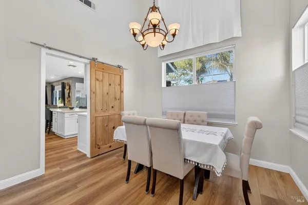 a large kitchen with kitchen island a stove a refrigerator a sink a dining table and chairs with wooden floor