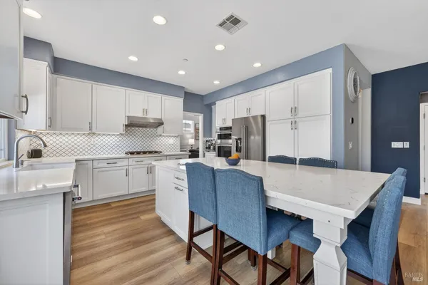 a kitchen with kitchen island a stove a table and chairs in it