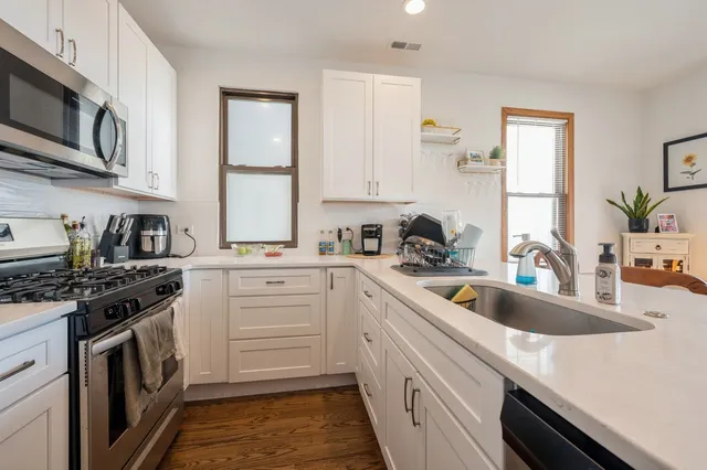 a kitchen with stainless steel appliances granite countertop a sink stove oven and white cabinets