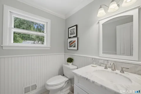 a bathroom with a granite countertop toilet a sink a mirror and a window