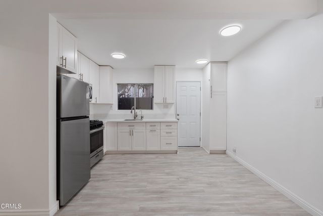 a large white kitchen with cabinets and stainless steel appliances