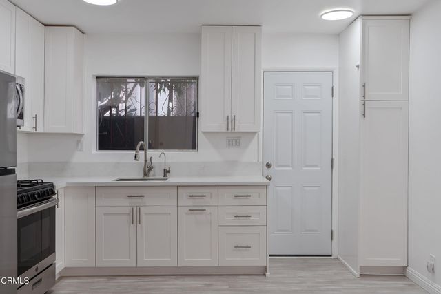 a kitchen with white cabinets and sink