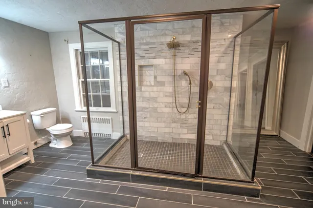 a bath room with a glass door shower and toilet