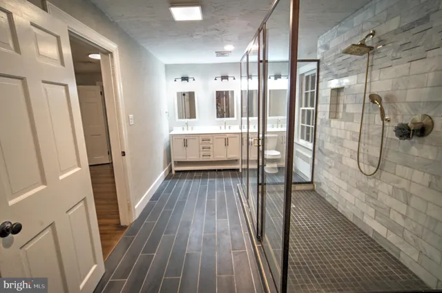 a bathroom with a glass door shower a sink and a mirror