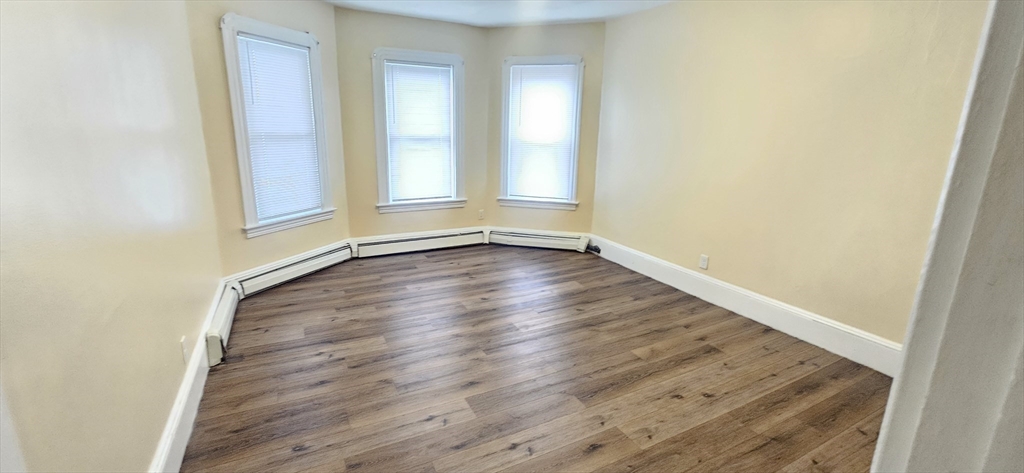 93 Arthur Street, Unit 3E Brockton, MA 02302 - Photo 3 of 8 an empty room with wooden floor and windows
