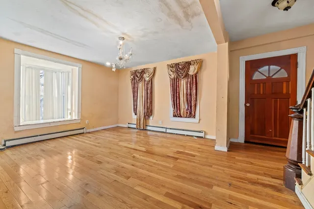 a view of an empty room with a window and wooden floor