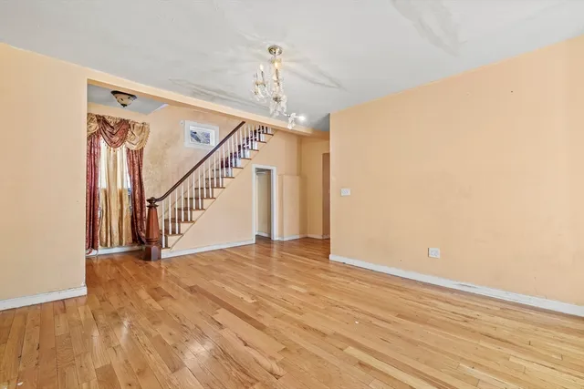 a view of an empty room with wooden floor and stairs