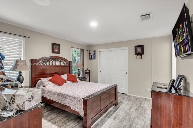 a bedroom with a bed and a potted plant on the dresser