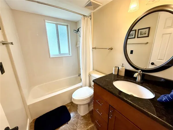 a bathroom with a granite countertop toilet sink and mirror