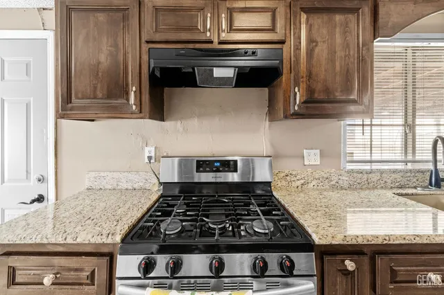 a kitchen with granite countertop a stove and a sink