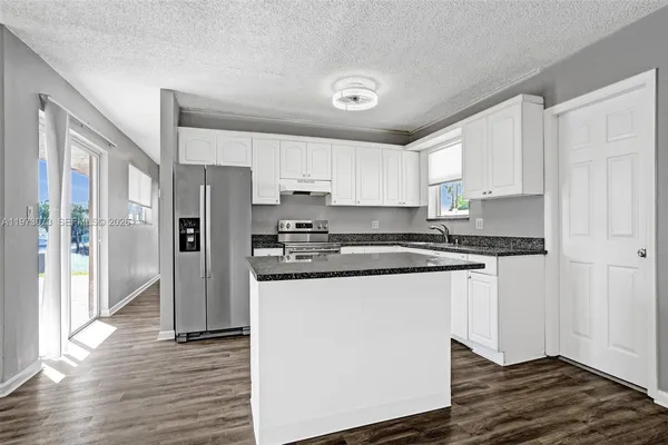 a kitchen with stainless steel appliances granite countertop a refrigerator and a stove top oven