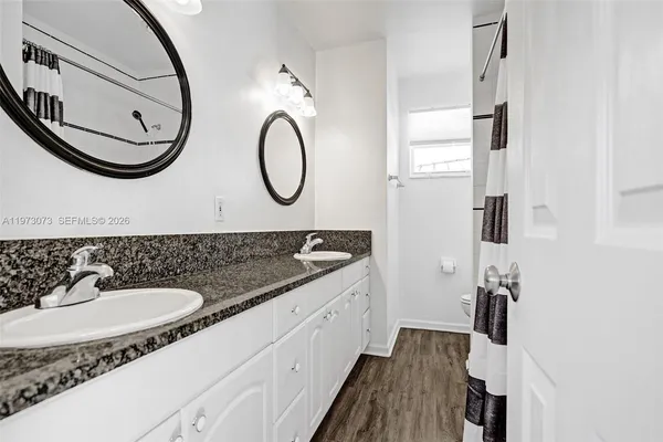 a bathroom with a granite countertop sink a mirror and a shower