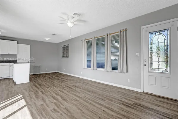 a view of an empty room with wooden floor and a window