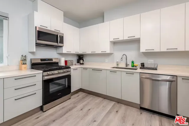a kitchen with granite countertop white cabinets and stainless steel appliances