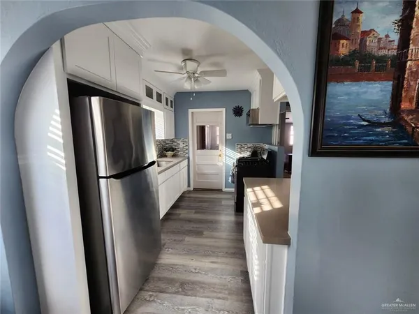 a hallway with wooden floor chandelier and livingroom