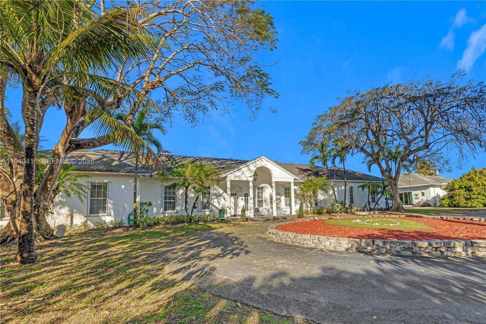 a view of a white house with a large tree