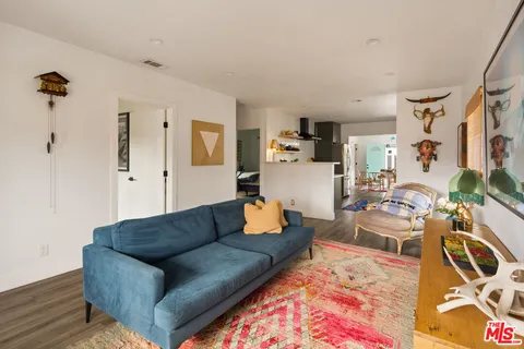 a living room with furniture a rug a mirror and a window