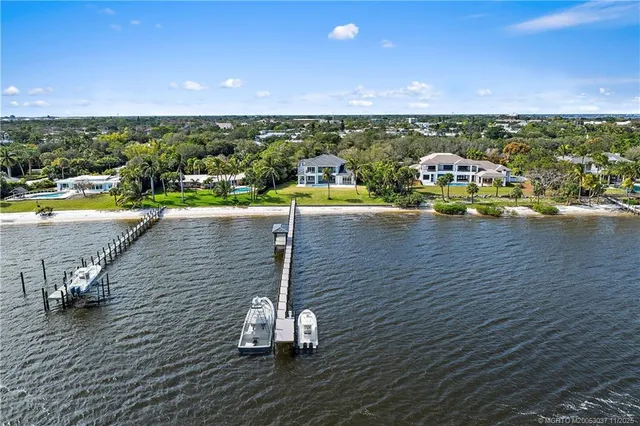 a view of a livingroom with a fireplace a chandelier a ceiling fan and front door