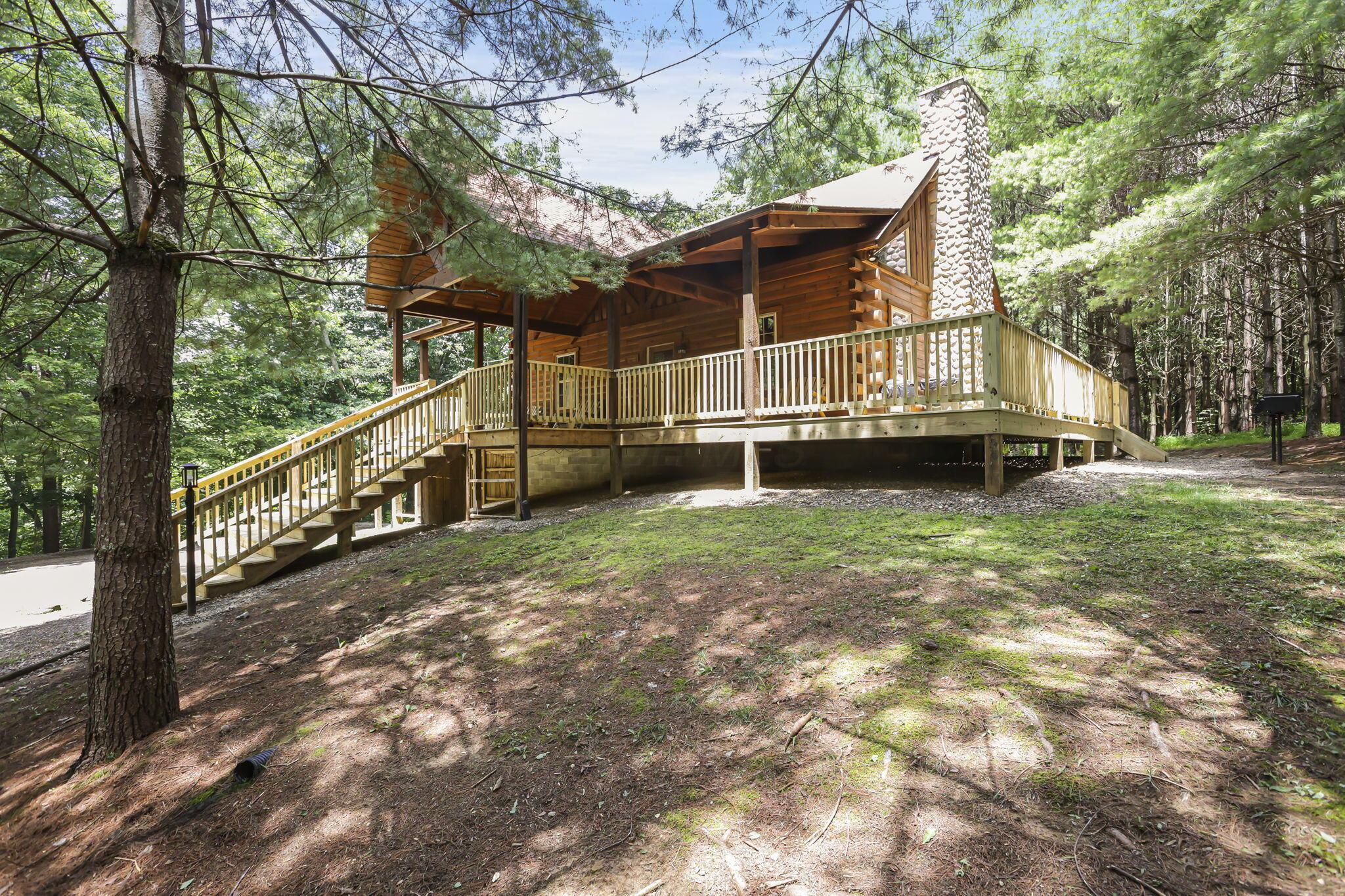 19475 Linden Road Logan, OH 43138 - Photo 8 of 94 Log cabin exterior featuring a stone chimney, extensive wood decking, and a covered porch