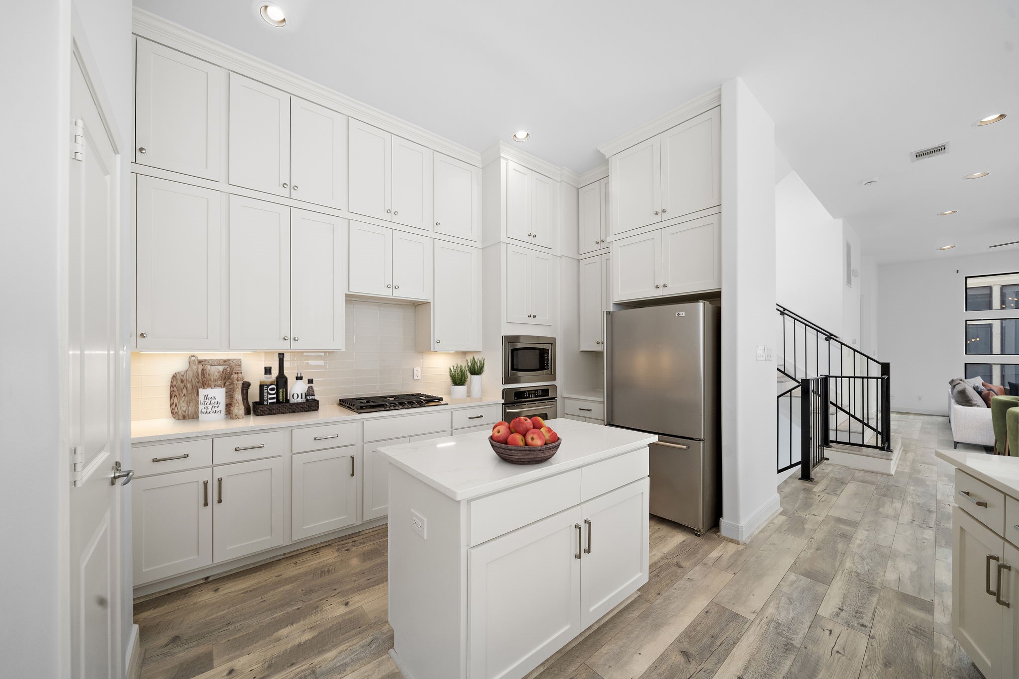 906 Reinerman Street Houston, TX 77007 - Photo 15 of 48 This modern kitchen boasts sleek white cabinetry, stainless steel appliances, and a stylish central island. Its open layout seamlessly connects to a bright living area with large windows, creating a spacious and welcoming ambiance.