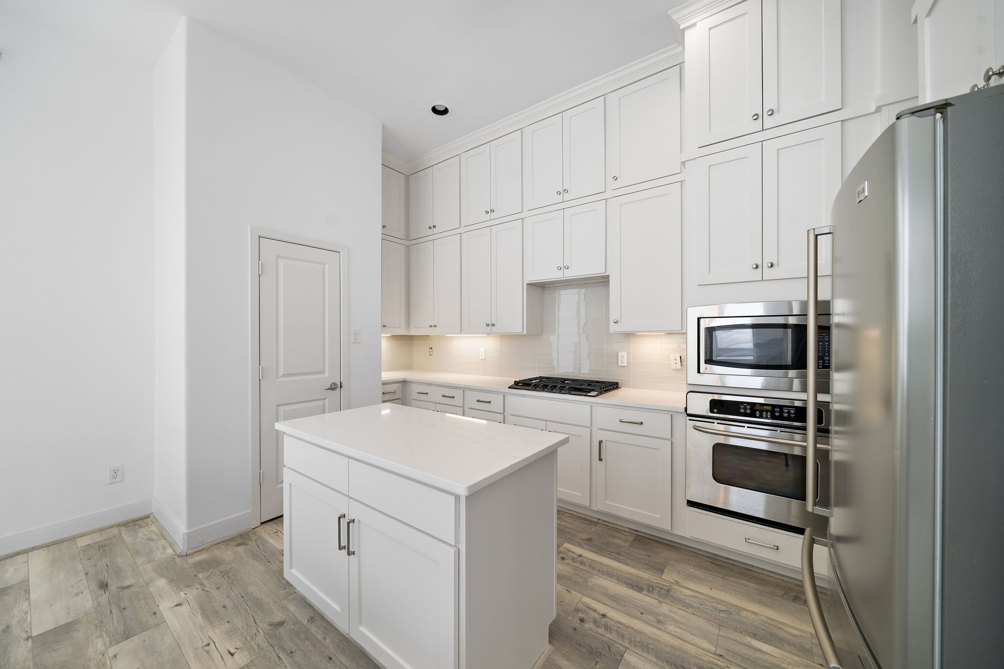 906 Reinerman Street Houston, TX 77007 - Photo 20 of 48 This modern kitchen features sleek white cabinetry, stainless steel appliances, and a central island. The space is bright and inviting, with light wood flooring and ample storage.