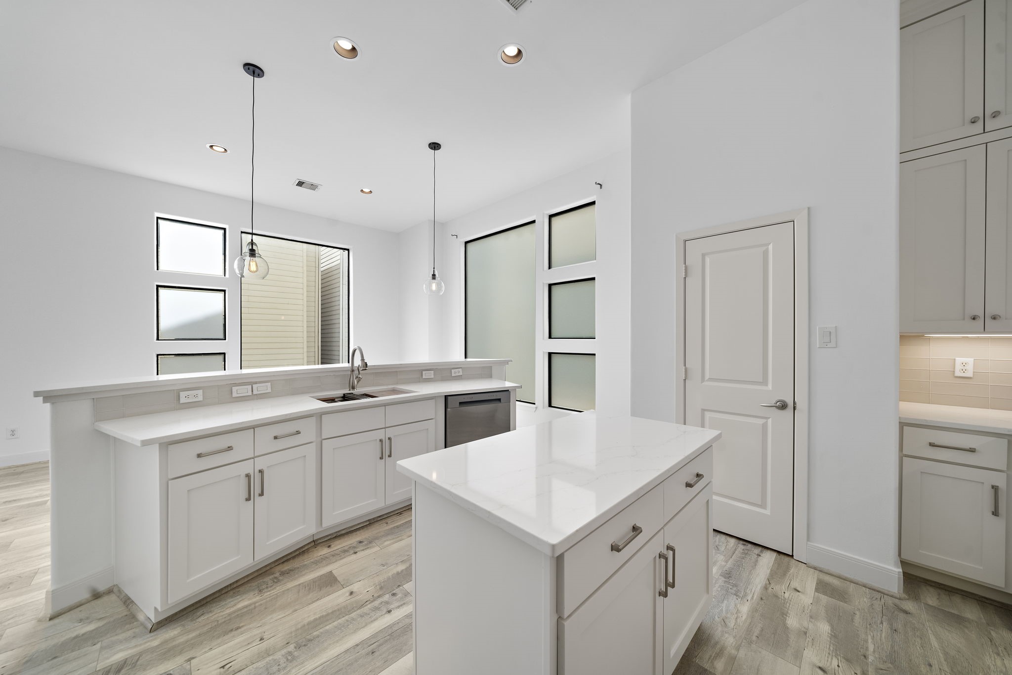 906 Reinerman Street Houston, TX 77007 - Photo 21 of 48 This kitchen features a modern design with white cabinetry, sleek countertops, and pendant lighting. It includes a central island, ample storage, and large windows for natural light, creating a bright, inviting space.