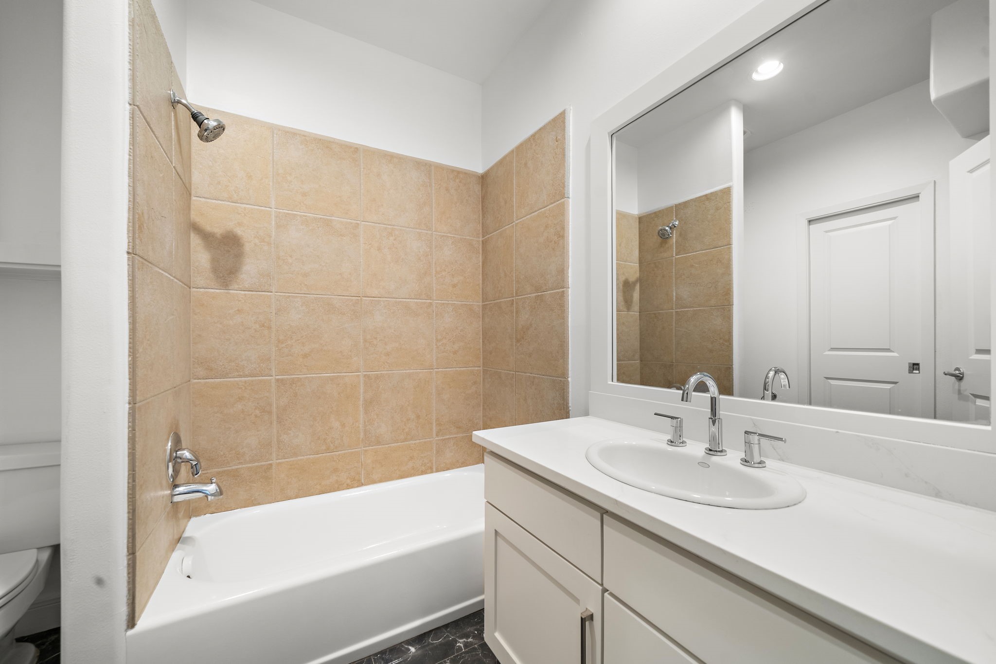 906 Reinerman Street Houston, TX 77007 - Photo 27 of 48 This bathroom features a clean, modern design with a white vanity and sink, large mirror, and a bathtub with neutral-toned tile surround. The overall look is sleek and inviting.