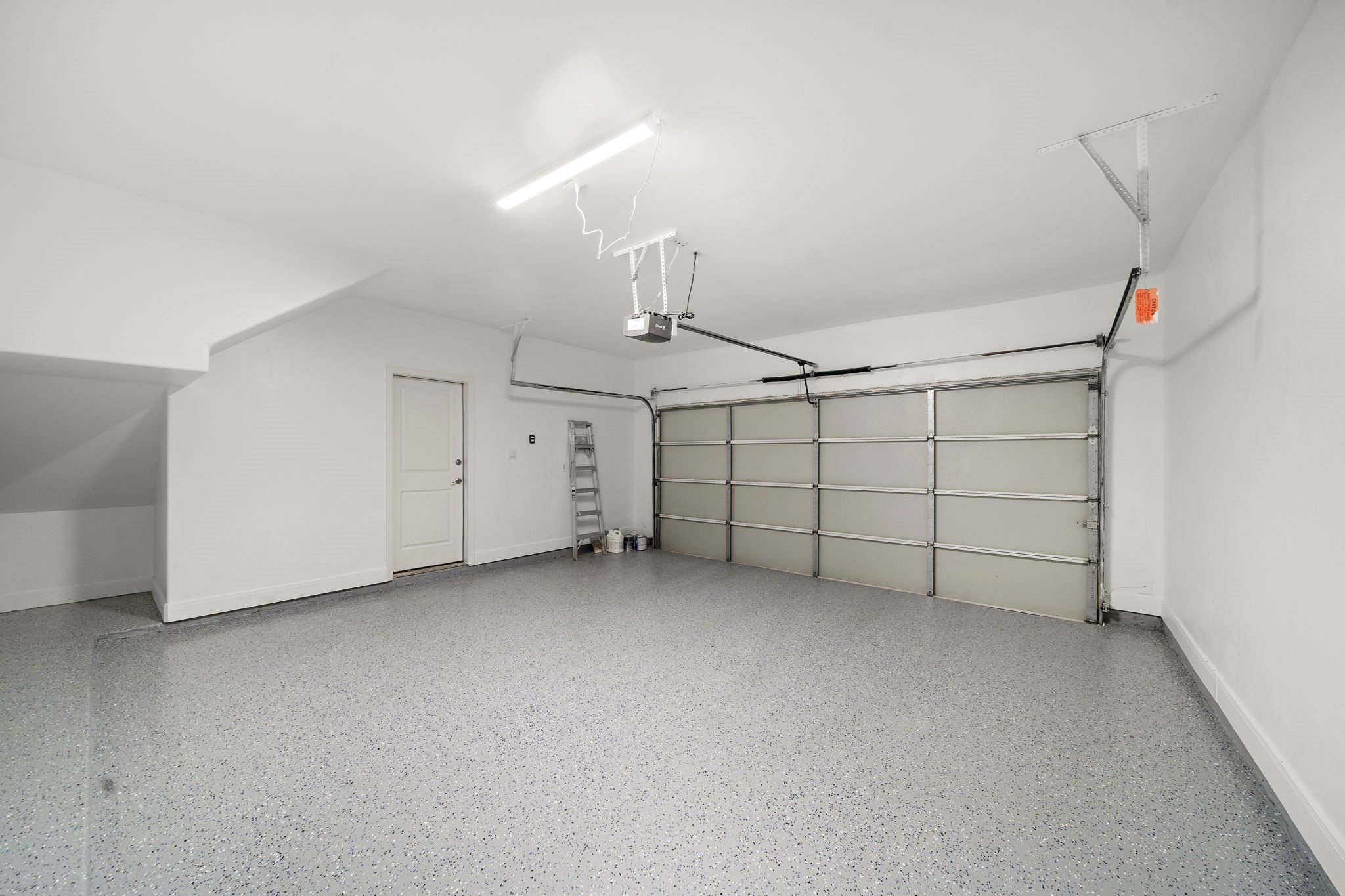 906 Reinerman Street Houston, TX 77007 - Photo 40 of 48 This spacious garage features a clean, well-lit interior with a durable, speckled floor finish. It includes a large automatic door and a side door for easy access to the house, providing ample room for vehicles and storage.