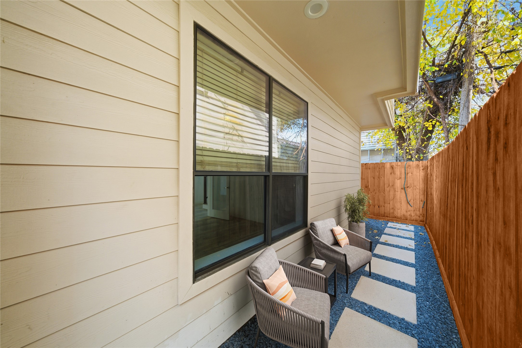 906 Reinerman Street Houston, TX 77007 - Photo 45 of 48 Charming outdoor space with a modern design, featuring a cozy seating area on a stone path, bordered by a wooden fence and siding. Ideal for relaxation and privacy (Virtual staging)