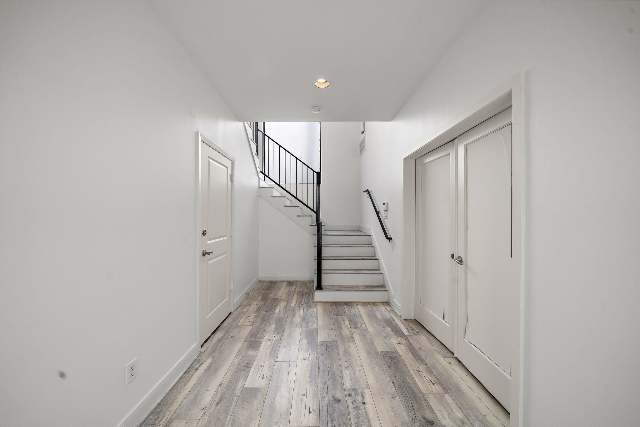 906 Reinerman Street Houston, TX 77007 - Photo 5 of 48 Step into a bright, modern entryway featuring sleek light wood floors, crisp white walls, and a stylish staircase with a black railing, offering a welcoming and spacious first impression.
