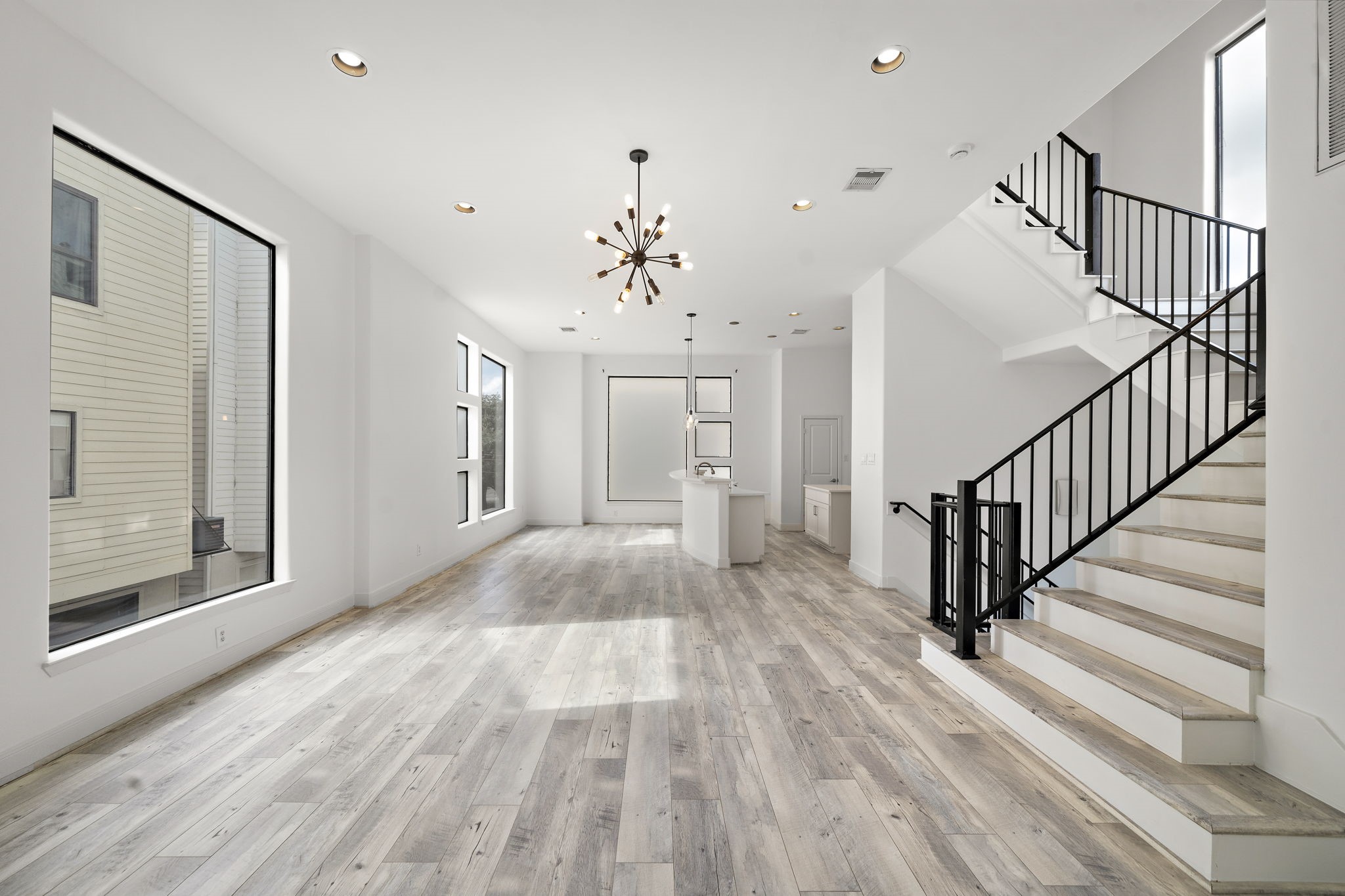 906 Reinerman Street Houston, TX 77007 - Photo 6 of 48 Modern and inviting, this spacious living area features sleek wood floors, abundant natural light from large windows, and a stylish staircase leading to the upper level. Perfect for contemporary living and entertaining.