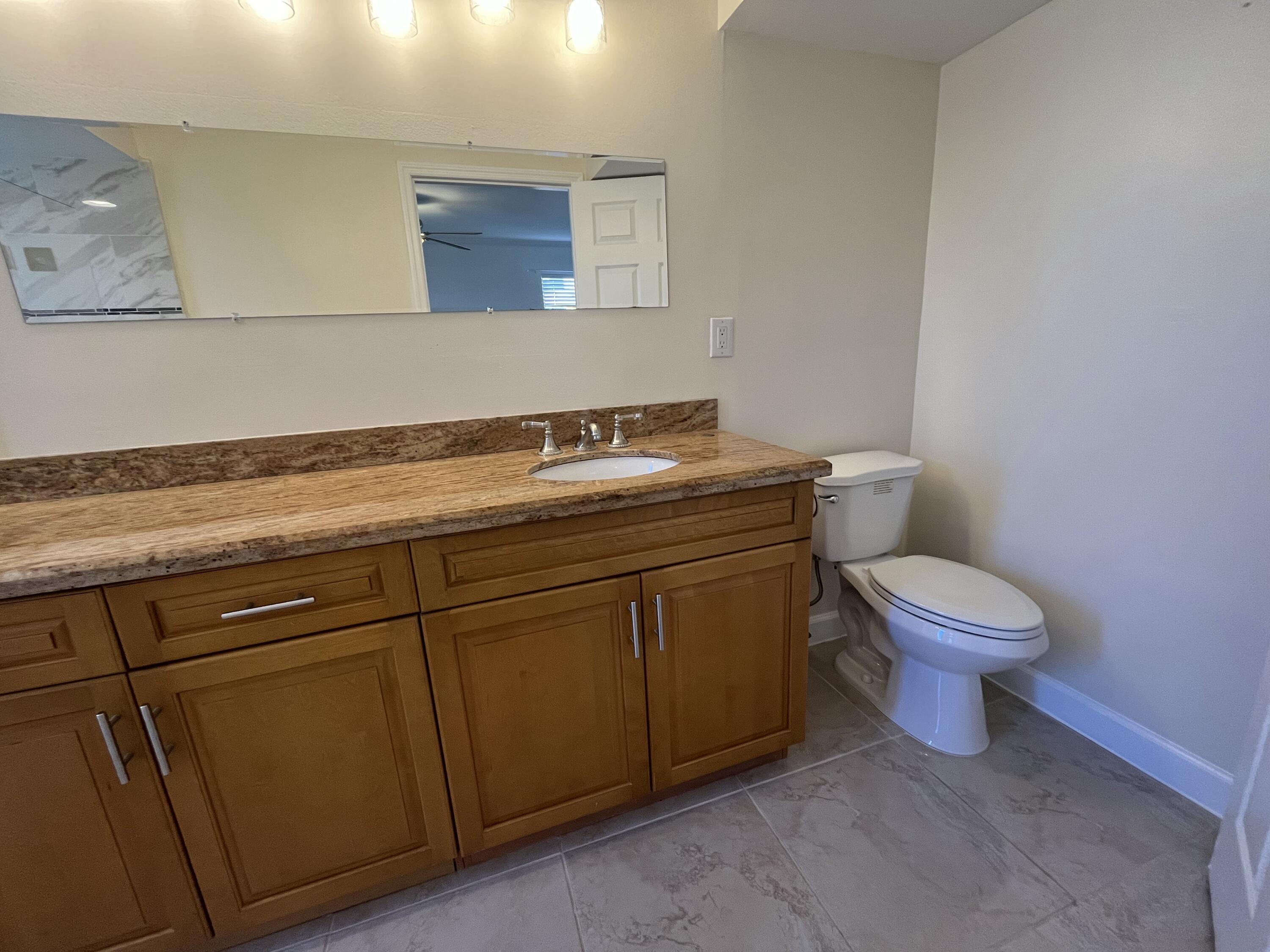 9300 Southwest 8th Street, Unit 301 Boca Raton, FL 33428 - Photo 17 of 27 a bathroom with a granite countertop toilet and a sink