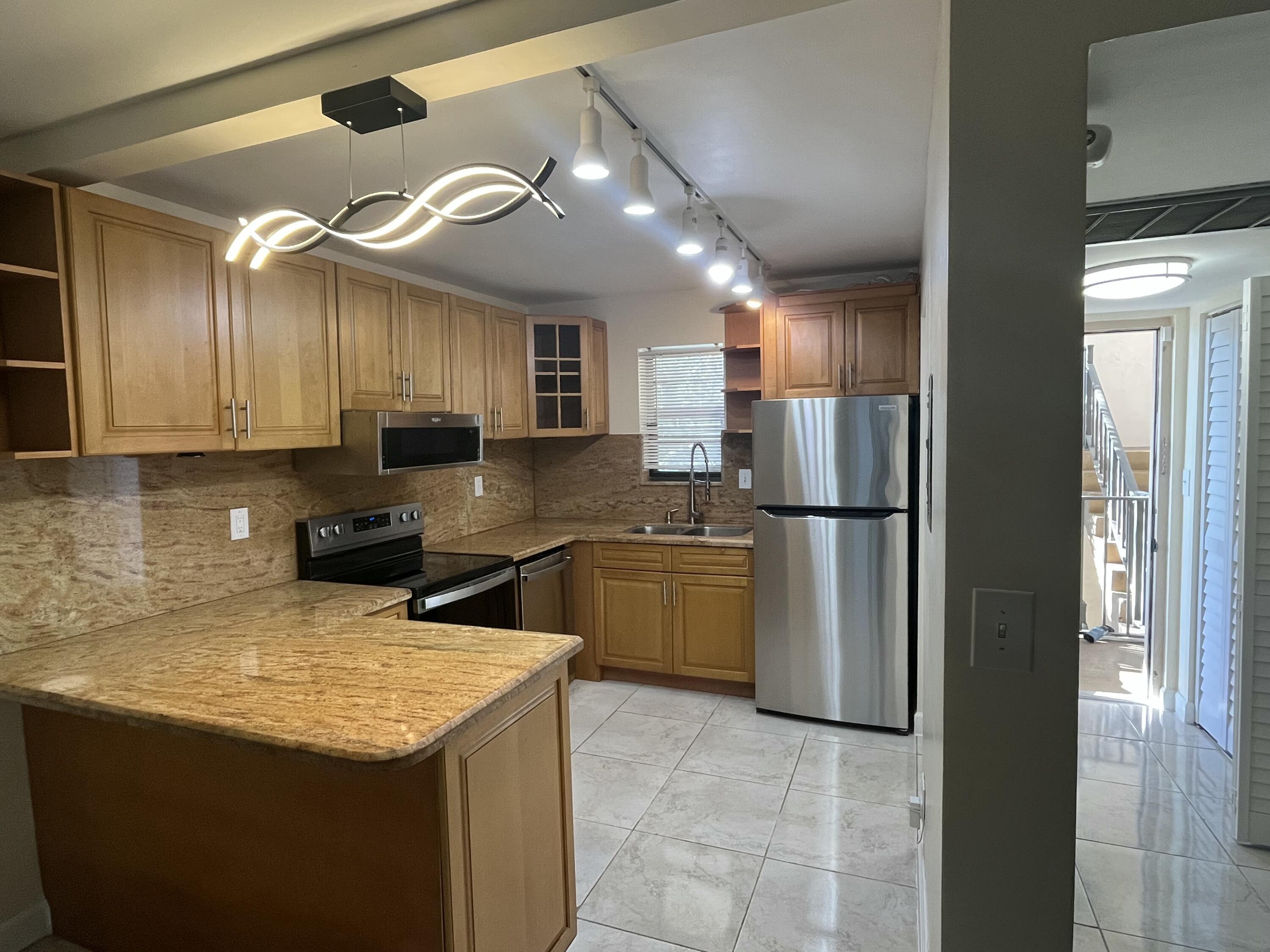 9300 Southwest 8th Street, Unit 301 Boca Raton, FL 33428 - Photo 3 of 27 a kitchen with a refrigerator a sink and cabinets